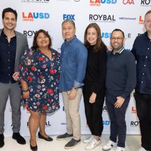 A team of seven posed in front of a screen with Roybal logos.