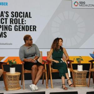 Three people on a stage being interviewed by a fourth with a microphone.