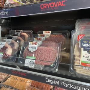 Various packages of fresh meats within a refrigerated case for retail presentation