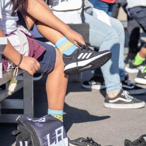 Students try on shoes on the playground during the Shoes That Fit event. 