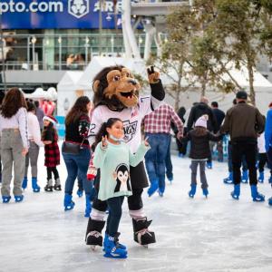 A child ice skates with LA Kings mascot Bailey at AEG's Community Ice Skating Party at L.A. LIVE.
