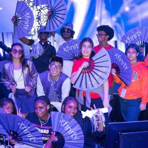 Students holding up purple fans with the xfinity logo