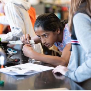 Young child stood at a table using a ruler