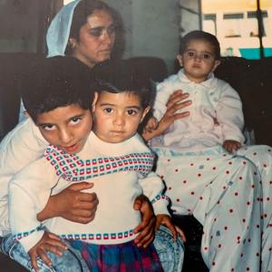 A family photo of a young child on a persons lap and two children sat together