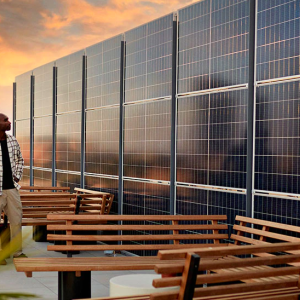 3 people standing in front of a wall of solar panels