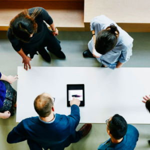 overhead view of group of workers at a table working with a tablet