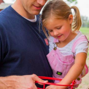 a man carrying a little girl who is putting eggs in a basket
