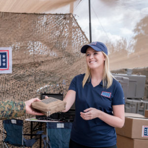 Woman from USO handing something to a soldier