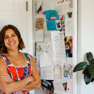 Sensi Graves stood against a white door, next to a pin board