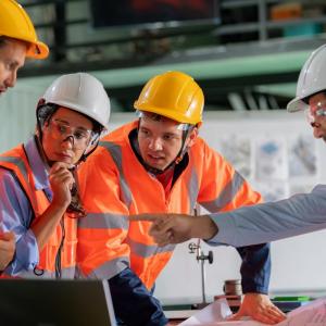 Four EHS professionals in safety gear discussing plans