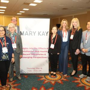 A group posed by a sign "Mary Kay" in a conference room.