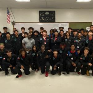 A group of students and adults posed in a classroom.