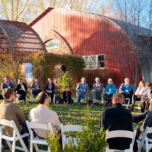 People sit outside in chairs arranged in a circle