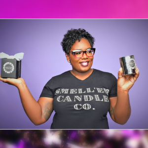 Shantell Jennings wearing a  Smell’em Candle Company t-shirt and holding her candles