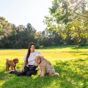 Young woman seated on the grass with her two dogs.