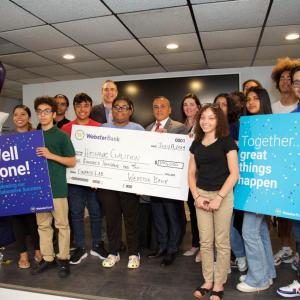 Group holding an oversized check and celebratory signs
