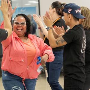 A smiling woman high-fives a Coach volunteer