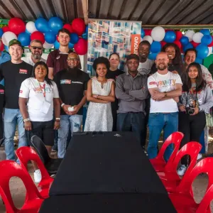 Group of people stood together for a photo, in front of a balloon garland