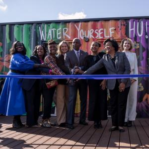 8 people cutting ribbon of a SheCare pod at Hampton University