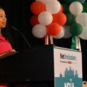 A person talking into a microphone on stage