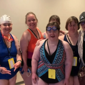 People in swimwear standing in group smiling at camera