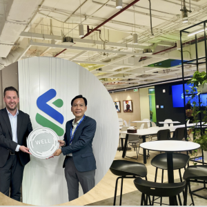 Two people standing with a WELL plaque