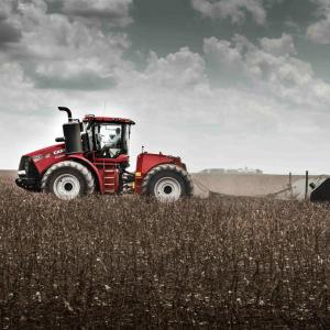 A large farm tractor harvesting crops in a field.
