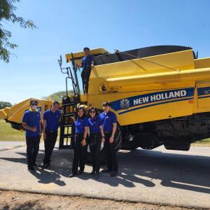 Five students standing in front of a New Holland Tractor