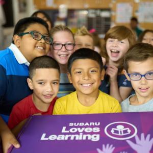 Group of young students holding a box reading, "Subaru loves Learning"