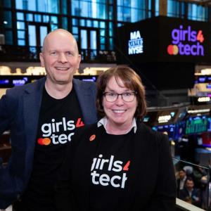 Two people posed looking above the floor of the new york stock exchange.