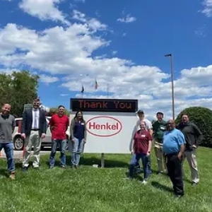 9 people in front of thank you Henkel sign