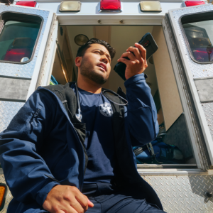 person sitting outside ambulance speaking on phone