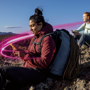 Two people looking at phones on a mountaintop