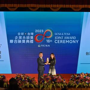 two people holding an award on stage with a blue and white projection behind them