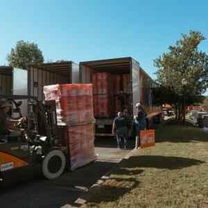Forklifts loading pallets of supplies onto trucks.