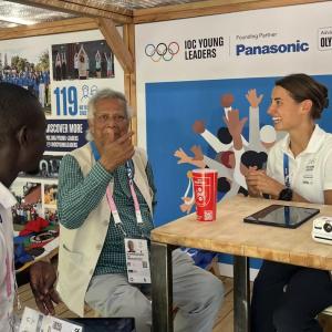 Three people sat around a table talking to each other 
