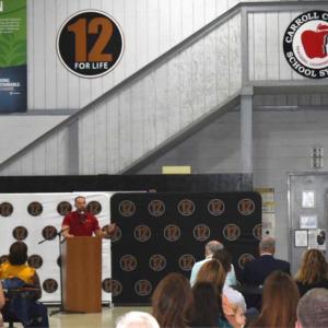A person talking into a microphone in front of an audience
