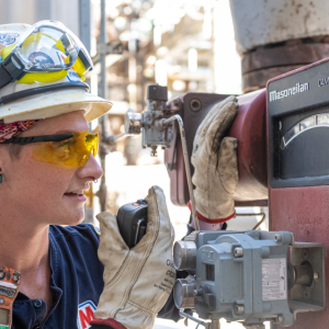 Tara Chippewa using a radio communicator while looking at a meter.