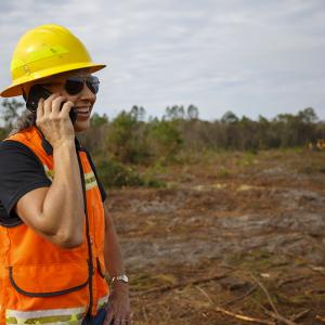 Terri on a cell phone, smiling, overlooking a cleared path