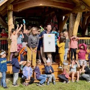 Students cheer as adults flip a life-size light switch at outdoor classroom