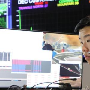 Thomas Doan wearing a headset, looking at multiple monitors.