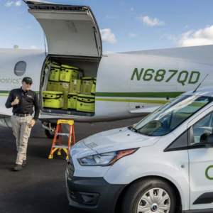A person giving a thumbs up whilst walking in front of an aeroplane 