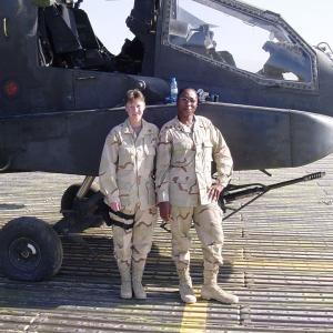 Tinisha Roberts in military uniform next to another person in front of a helicopter.