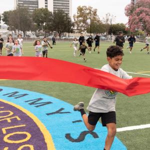 Local soccer youth fun through the red ribbon at centerfield of "Tommy's Field" to declare the pitch open to the public. 