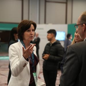 Tracey Campbell talking to another person in a room of others.