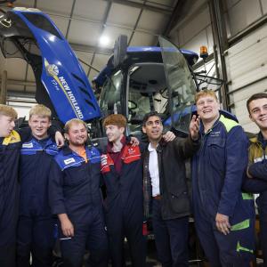 UK Prime Minister, Rishi Sunak, stood infront of a blue tractor with New Holland engineering apprentices 