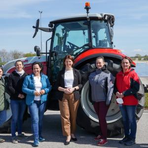 Women students stand in from of a tractor