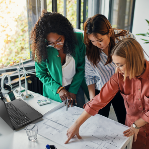 Three woman looking at blueprints together