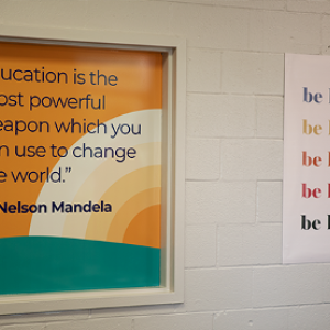 two signs reading: "education is the most powerful weapon which you can use to change the world" and "be kind"
