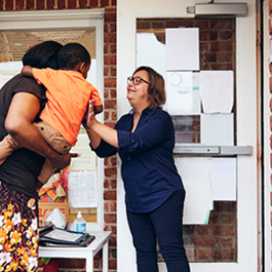 woman holding small child passing off to other woman
